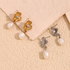 Détail de boucles d'oreilles fleurs plaquées or 18 carats et perles irrégulières