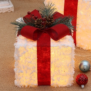 White flocked Christmas gift boxes with red velvet ribbons and LED lights for holiday decor