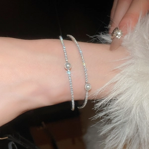 Close-up of double-layered silver bracelets with sparkling zircon and elegant pearls