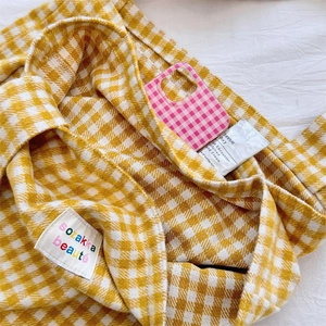 Detailed close-up of yellow plaid wool fabric texture and embroidered brand woven label