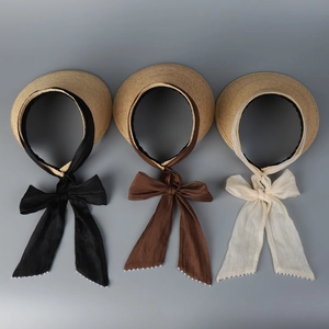 Detailed view of straw sun visors with elegant silk bows and decorative pearls in three colors