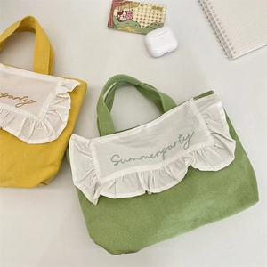 Detail of embroidered Summerparty canvas lunch bags with ruffled edges and vibrant colors