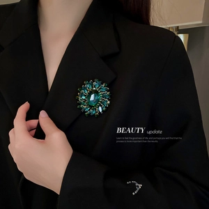 Vintage emerald flower brooch with sparkling diamonds on a black blazer for women