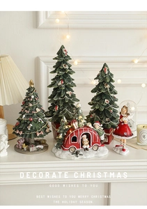 Miniature resin Christmas trees and doll figurines on a mantel with warm holiday lights