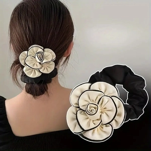 Detail of cream camellia flower hair scrunchie with black trim and fabric texture
