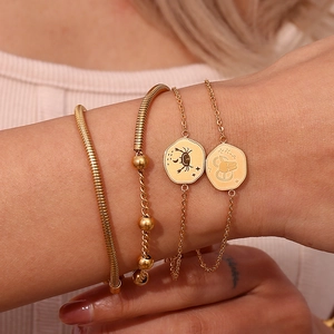 Detail showing a layered set of four gold snake and beaded chains with zodiac charms