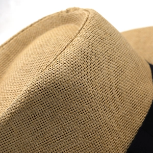 Gros plan détaillé sur la texture de la paille tressée et le ruban noir décoratif du chapeau