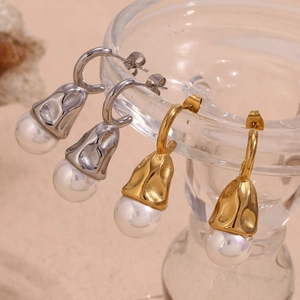 Detail of gold and silver hammered metal drop earrings with elegant pearl pendants