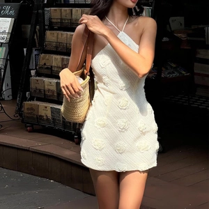 Détail d'une robe dos nu blanche avec fleurs 3D et texture en maille travaillée