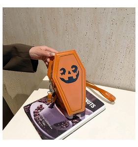 Close-up of orange coffin-shaped crossbody bag with black pumpkin face and glossy finish