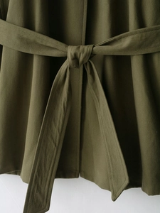 Detail of army green cotton trench coat featuring a knotted waist belt and twill texture