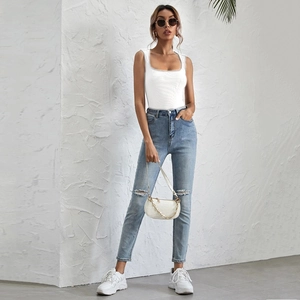Detail of white ribbed U-neck slim fit tank top paired with light washed ripped jeans