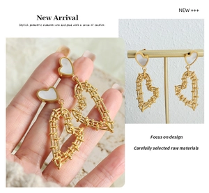 Detail of gold heart earrings featuring woven hollow design and white shell inlay