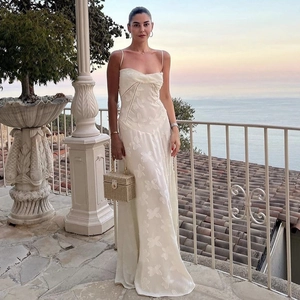 Close-up of white maxi dress with textured floral embroidery on seaside terrace