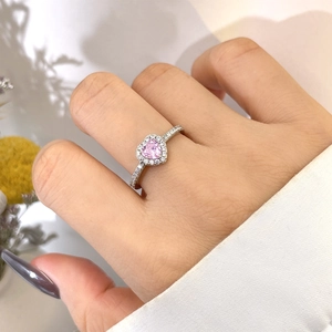 Close-up of heart-shaped pink gemstone ring with halo diamonds on a silver band