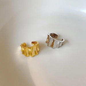 Macro detail of textured wave design ear cuffs in polished gold and silver finishes