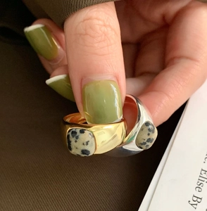 Detail of minimalist gold and silver rings set with square Dalmatian Jasper stones