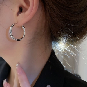 Gros plan d'une créole en argent minimaliste sur modèle avec finition miroir poli