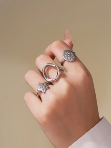 Detail of silver five-point star and geometric rings set with cubic zirconia on model hand