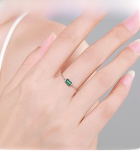 Close-up of a delicate silver chain ring featuring a rectangular green zircon stone
