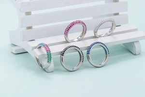 Fashionable micro-pave zircon rings in five vibrant colors displayed on a white bench