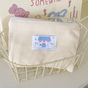 Piccola borsa in velluto a coste crema con toppa blu a forma di casa in un cestino