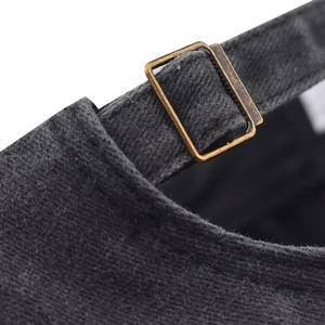 Close-up of vintage bronze buckle and adjustable fabric strap on washed grey cotton cap