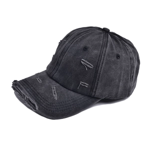 Detail of distressed ripped edges on a vintage washed black denim baseball cap