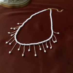 Close-up of pearl choker with golden fringe tassels on dark velvet background