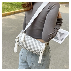 Detail of checkered cylinder crossbody bag featuring grey and white weave with wide strap