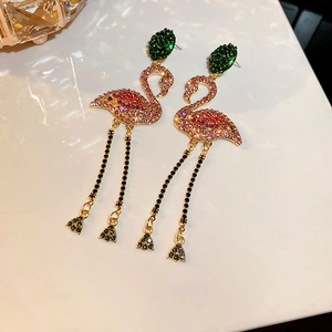 Macro shot of flamingo earrings featuring pink rhinestones and gold chain tassels