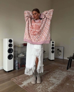 Detail of soft oversized knit sweater with fringe skirt and platform boots in a cozy room