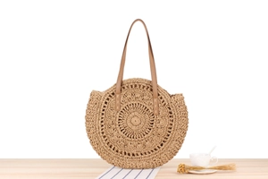 Detail of round straw beach bag featuring concentric woven patterns and leather strap