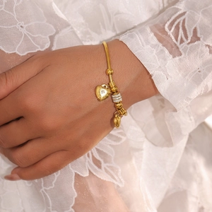 Elegantes goldenes Schlangenarmband mit Herzanhängern aus Kristall auf weißer Spitze