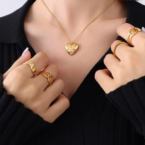 Golden heart pendant necklace with star crystal and multi-style rings set on a model