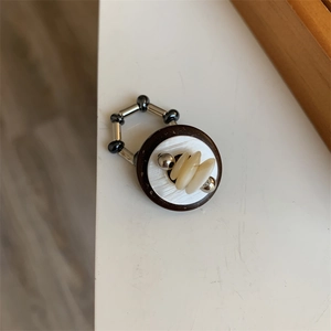 Detail of vintage beaded stretch ring with brown base, white shell, and silver metal beads