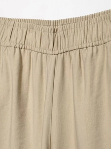 Detail of khaki wide-leg pants featuring an elastic waistband and fine twill texture