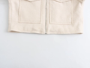 Vue détaillée de la veste en laine beige montrant l'ourlet avec fermeture éclair et poches plaquées