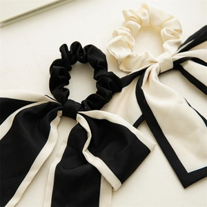 Close-up of elegant black and white silk satin bow scrunchies with long flowing ribbons