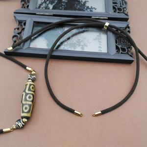 Braided necklace rope with Tibetan Dzi bead pendant on a wooden background