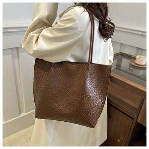 Detail of dark brown tote bag with embossed woven texture shown on a beige trench coat