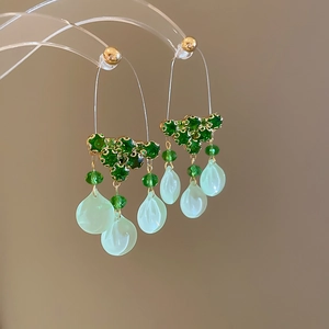 Detailed close-up of long tassel earrings with green crystals and glass petals