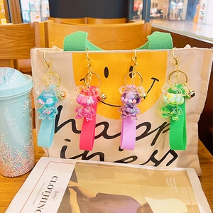 Cartoon glitter bear liquid keychains in four colors hanging on a canvas bag