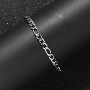 Macro shot of 5mm silver stainless steel Figaro chain links on a black display stand