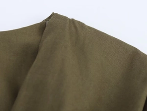 Gros plan du tissu tissé vert olive montrant les coutures de l'épaule et la texture