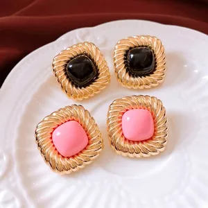 Vintage square gold twist earrings with black and pink accents on white porcelain