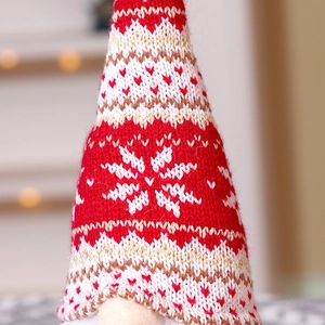 Close-up of knitted Christmas gnome showing red snowflake patterns and heart textures