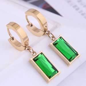 Macro shot of gold rectangle emerald earrings with geometric green step-cut gemstones