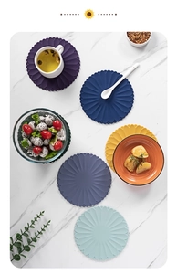 Overhead view of flower-shaped silicone placemats in five colors on a marble table