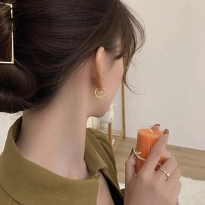 French style gold twisted hoop earrings and ring worn by model in a soft home setting